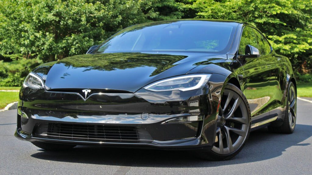 The Tesla Model S Plaid electric sedan speeding on an open road, showcasing its sleek design and high-performance capabilities.